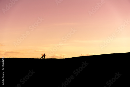 Unknown couple hiking in silhouette at sunset © Luis