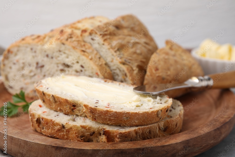 Tasty bread with butter and knife on table, closeup