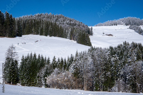 A group of snowshoers trace a path up the mountain. Mountainous winter landscape in the Spitzstein area, Tyrol, Austria, sun, blue sky.