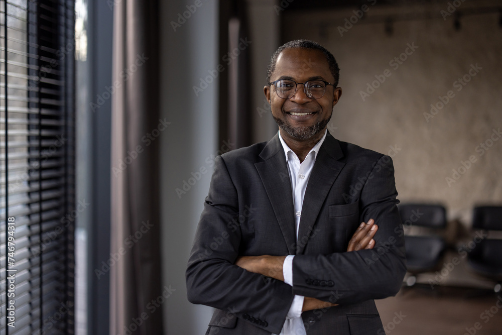 Confident african american businessman standing with arms crossed in office Confident african american businessman standing with arms crossed in office