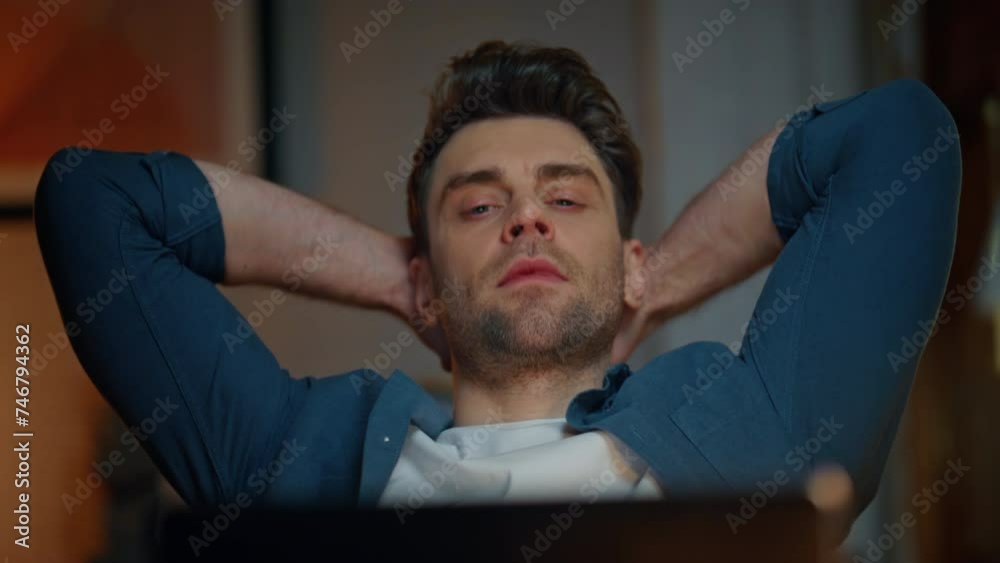Relaxed man looking laptop at night workplace closeup. Guy stretching arms alone Relaxed man looking laptop at night workplace closeup. Guy stretching arms alone