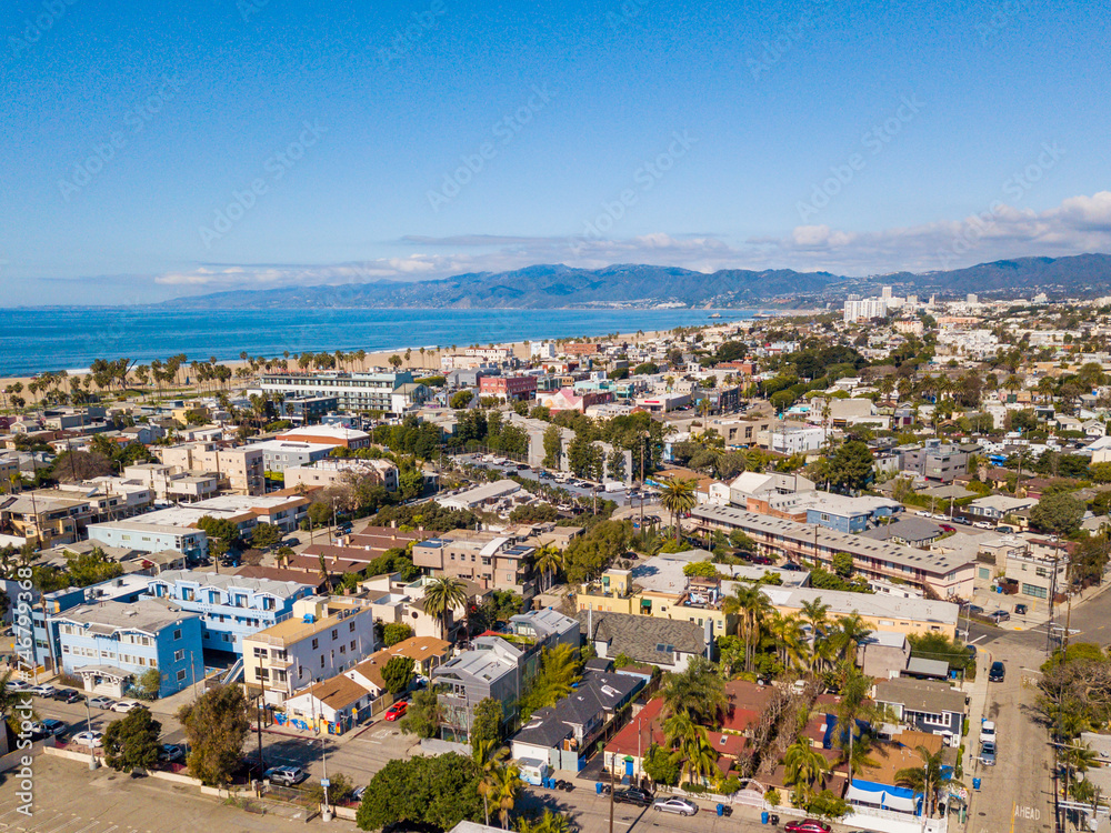 Aerial drone view over Venice looking towards the beach and the Santa Monica Mountains on a clear blue sky day.