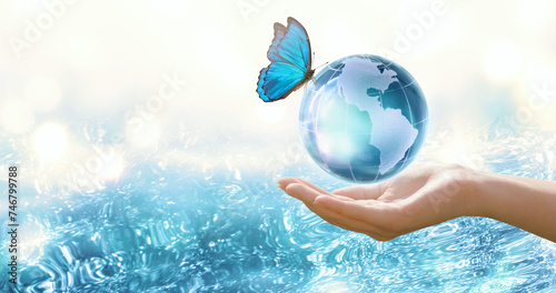 Water Day or World Oceans Day concept. Environmental conservation, save, protect clean planet Earth and ecology, sustainable lifestyle. Globe and Morpho Butterfly in human hand on pure sea background.