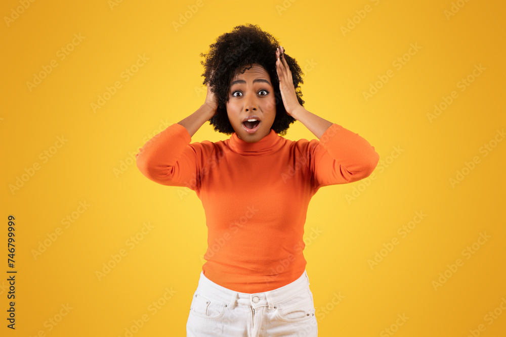 Surprised young woman with afro hair, wearing an orange sweater and white pants Surprised young woman with afro hair, wearing an orange sweater and white pants