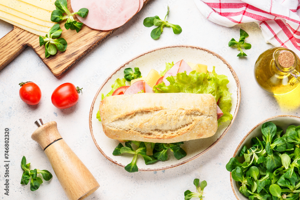 Ciabatta sandwich with lettuce, cheese, tomatoes and ham on white table. Ciabatta sandwich with lettuce, cheese, tomatoes and ham on white table.