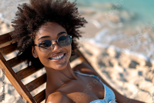 Portrait of a happy young African-American woman relaxing on a wooden deck chair on a tropical beach.