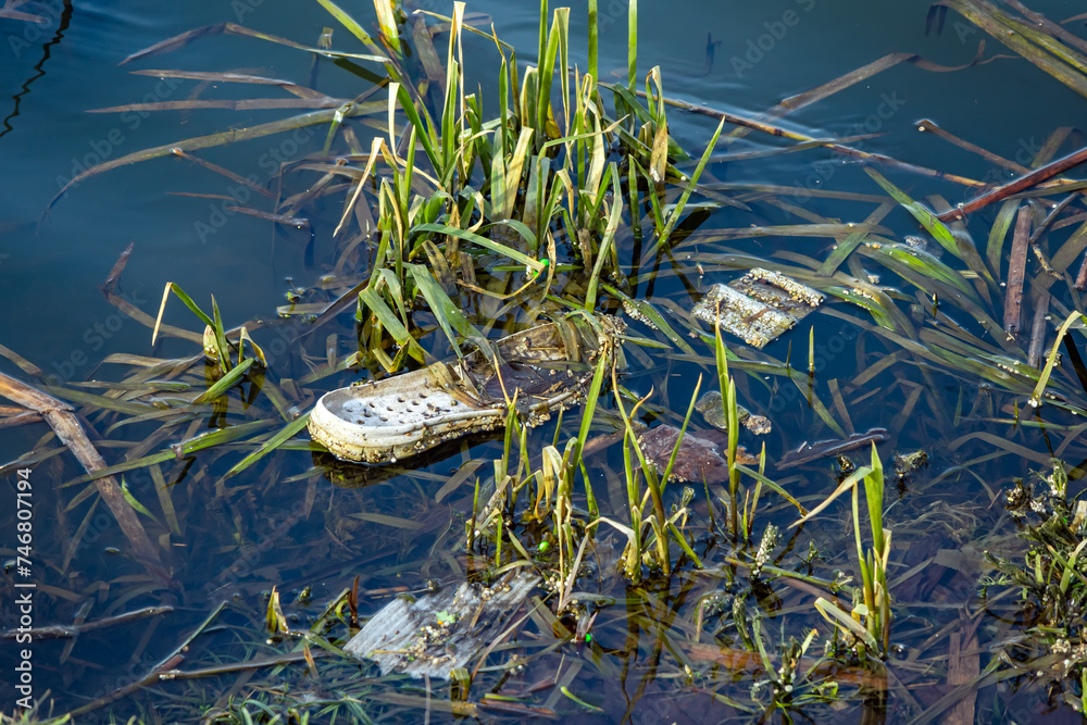 Trash on the river bank. Water pollution by garbage is an environmental problem Trash on the river bank. Water pollution by garbage is an environmental problem