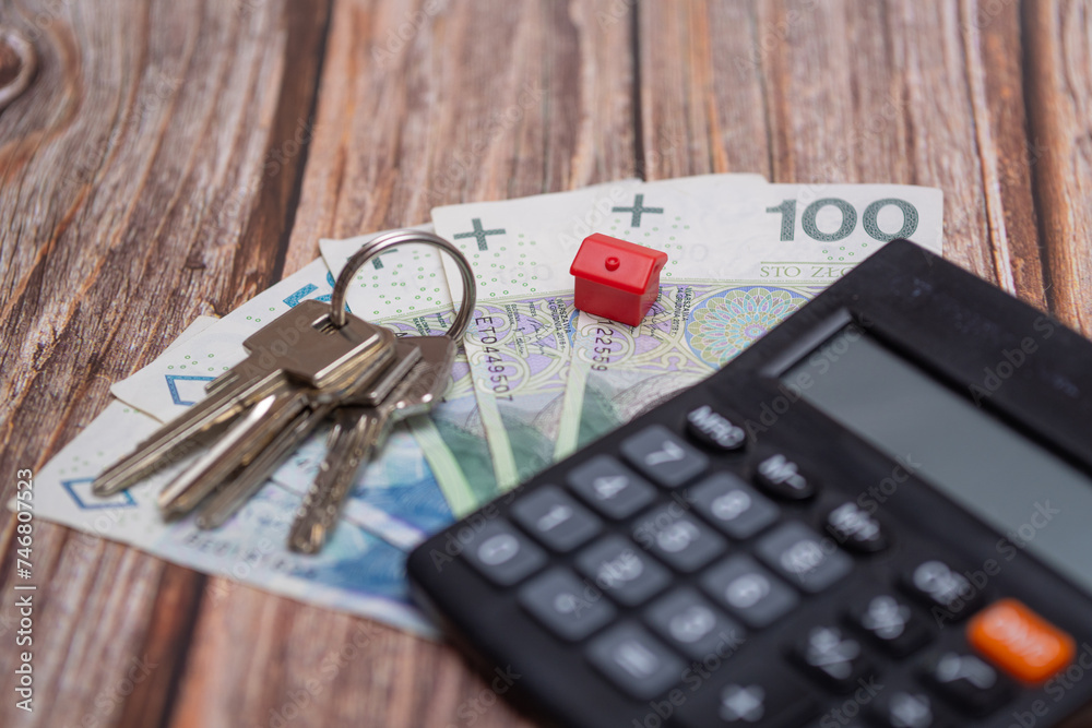 close-up of Polish money next to a calculator, keys and a small house. A concept showing the housing market in Poland close-up of Polish money next to a calculator, keys and a small house. A concept showing the housing market in Poland