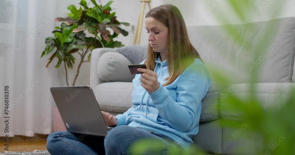 Woman in blue hoodie using laptop and holding credit card Woman in blue hoodie using laptop and holding credit card