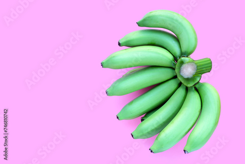 Green banana on pink background. © Bowonpat