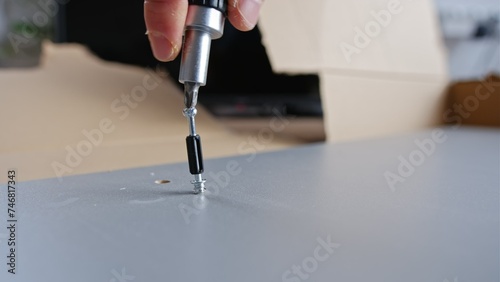Caucasian Male Hnadyman Putting Together Self Assembly Furniture using Eccentric Connector Bolt Screw and Screwdriver photo