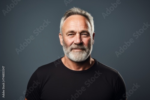 Portrait of a senior man with grey hair and beard. Isolated on grey background. © Inigo