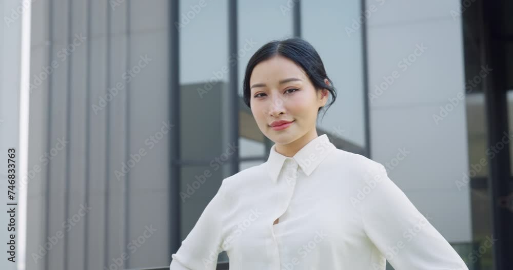Confident Asian businesswoman in a white blouse stands poised against a backdrop of modern office buildings. Confident Asian businesswoman in a white blouse stands poised against a backdrop of modern office buildings.