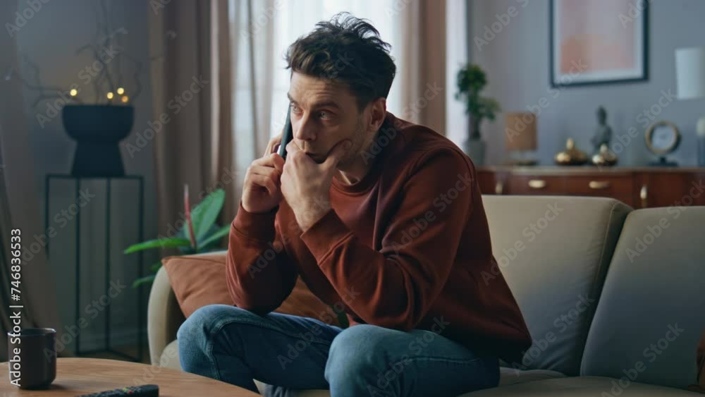 Unhappy man worried call sitting couch close up. Upset guy talking mobile phone Unhappy man worried call sitting couch close up. Upset guy talking mobile phone