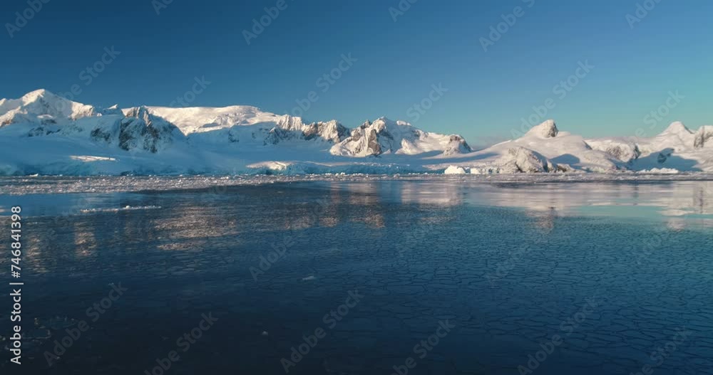 Polar frozen ocean landscape, ice on water surface. Snow covered mountain range, blue sky, sunny evening. Winter background. Breathtaking harmony of untouched nature. Scenery overview. Static shot. Polar frozen ocean landscape, ice on water surface. Snow covered mountain range, blue sky, sunny evening. Winter background. Breathtaking harmony of untouched nature. Scenery overview. Static shot.