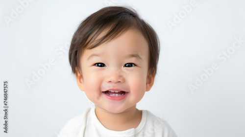 Closeup of a happy little Asian or Chinese toddler girl smiling, studio photography. Adorable female preschooler, innocent daughter looking at the camera, isolated on a white background