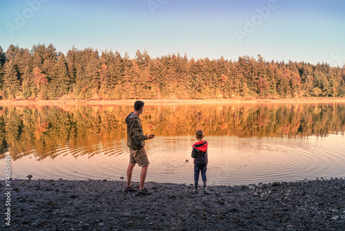 Happy Father and Son child and dad playing by a Lake. kid and parent play in nature. Fatherhood, and family childhood concept