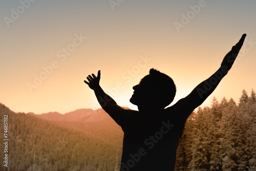 Life if Beautiful! Young Man Facing Mountain Sunset Rejoices, smiles looking up to the sky, enjoys life and summer, nature, adventure and feelings of freedom, hope, and happiness