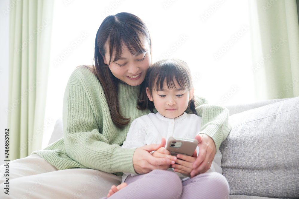 Image of a parent and child (mother and daughter) happily looking at a smartphone Playing together with apps and videos
