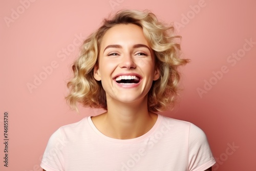 Portrait of a happy young woman with blond curly hair over pink background