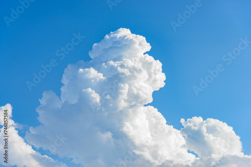 Cumulus white clouds bofies towering in clear blue sky background.