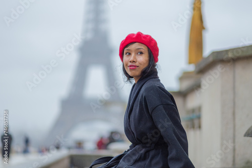 Young beautiful happy woman in red French beret in Paris, France against Eiffel Tower.  European tourism and travels to the capital cities #746857758