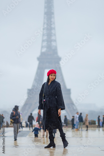 Young beautiful happy woman in red French beret in Paris, France against Eiffel Tower.  European tourism and travels to the capital cities
