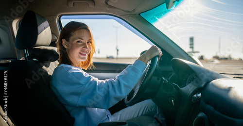 фотографія A beautiful woman driving a car in summer smiles successfully