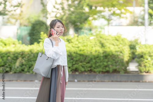 A young Japanese woman in her 20s walking while talking on a smartphone in the streets of Nagoya City, Aichi Prefecture 愛知県名古屋市の街なかでスマートフォンで通話しながら歩く２０代の若い日本人女性 © Hello UG