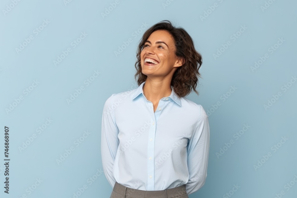 Portrait of a happy businesswoman laughing and looking up over blue background Portrait of a happy businesswoman laughing and looking up over blue background