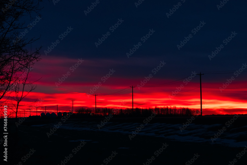 Fototapeta premium Dramatic red sunrise and the calm highway in prairies in winter.