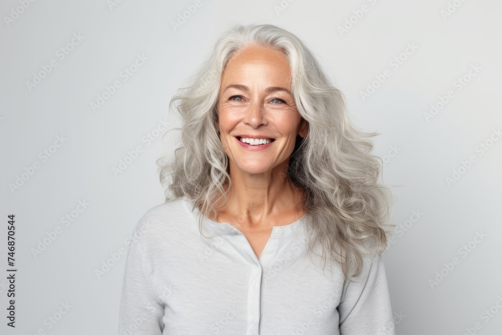 Portrait of a happy senior woman smiling at the camera against grey background Portrait of a happy senior woman smiling at the camera against grey background