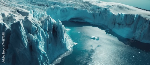An aerial perspective of a massive iceberg floating in the Arctic Ocean, showcasing the effects of the climate crisis as glaciers rapidly melt in the surrounding waters.