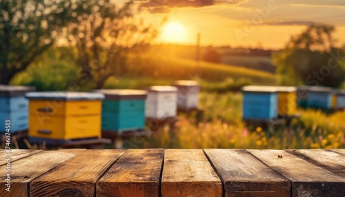 Empty wooden table top for product display. In the background, a blurred background of a small apiary at sunset. photo