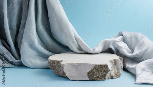 A broken stone podium displayed on a light blue background, decorated with a luxurious fabric. Empty space for cosmetic product presentation 