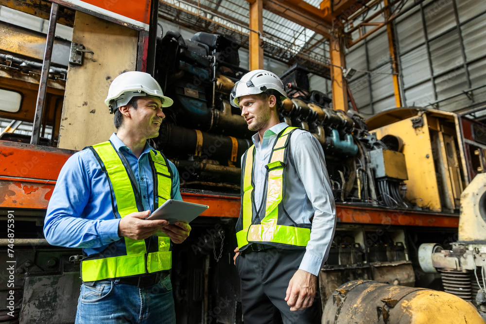 Railway technician engineer wearing safety uniform and safety helmet holding tablet check work plan standing at site railroad station. Locomotive repairman in factory. Railway technician engineer wearing safety uniform and safety helmet holding tablet check work plan standing at site railroad station. Locomotive repairman in factory.