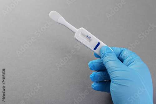 Doctor holding disposable express test on light grey background, closeup. Space for text