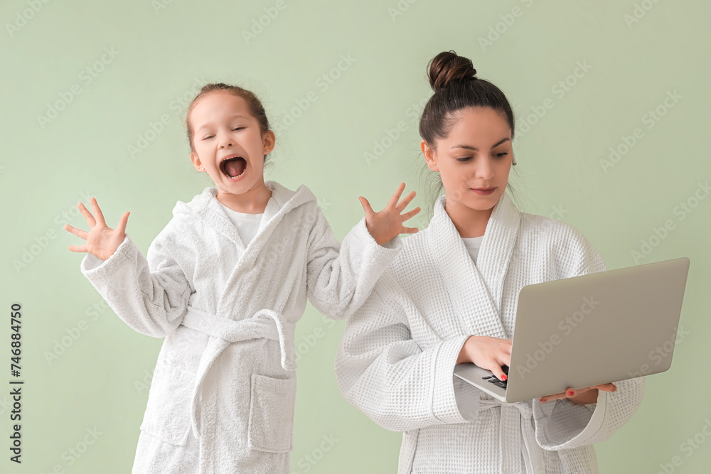 Naughty little girl with her working mother on green background Naughty little girl with her working mother on green background