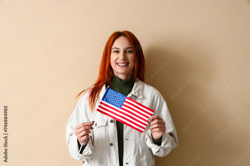 Fototapeta premium Young woman with USA flag on beige background