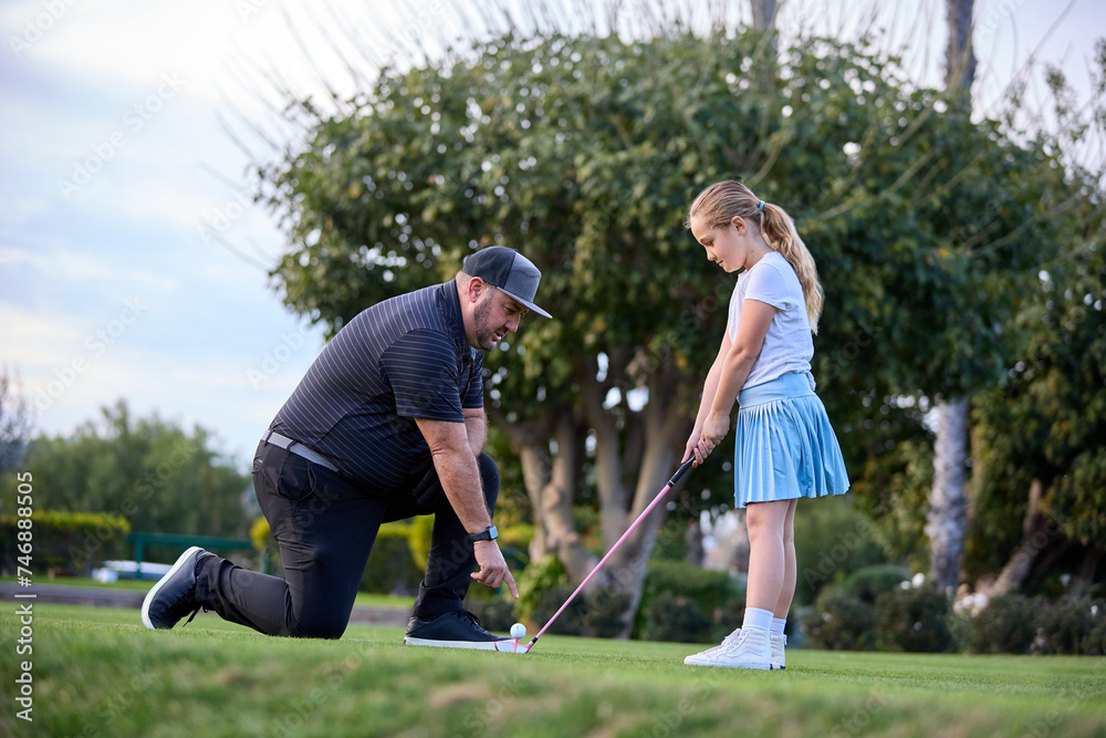 A father and Daughter play golf on a golf course A father and Daughter play golf on a golf course
