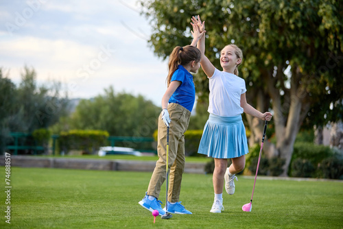 Картината върху платно Two young girls play golf on a tee box