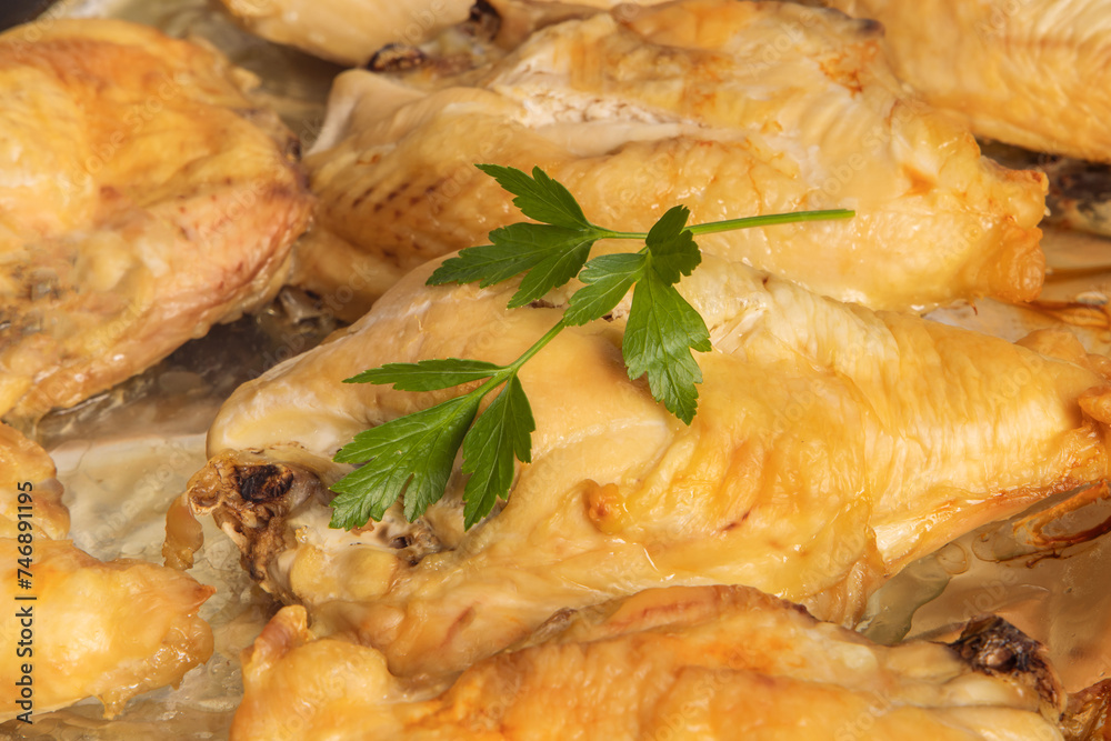A closeup of baked skin on chicken breasts in a tray in a restaurant kitchen with garnish