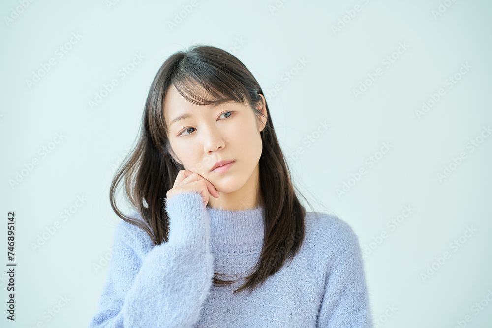 あごに手を当てて、考え事をしている若い女性 あごに手を当てて、考え事をしている若い女性