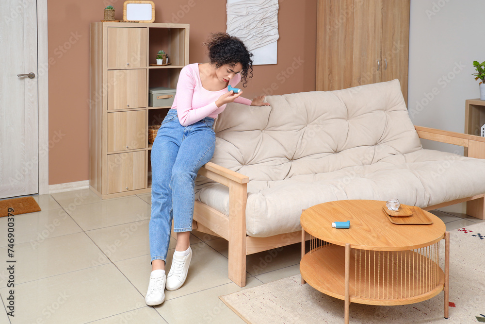 Young African-American woman using asthma inhaler at home Young African-American woman using asthma inhaler at home