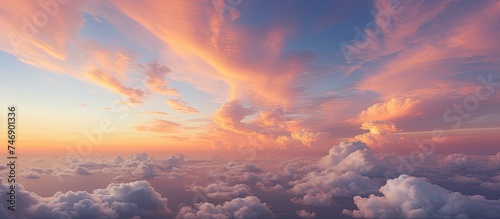 The image captures a cloudy sky during twilight at sunset as seen from an airplane window. The suns rays cast a warm glow on the clouds, creating a serene and peaceful atmosphere.
