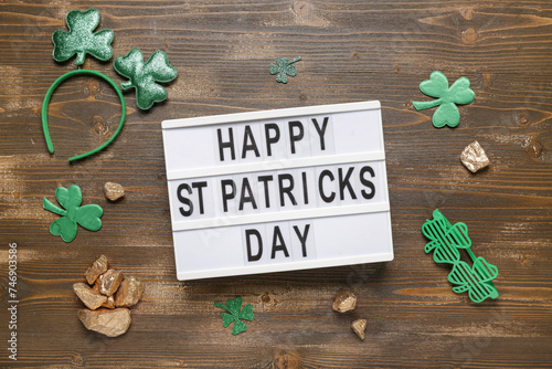 Board with words HAPPY ST PATRICKS DAY, plastic eyeglases and decor on wooden background photo