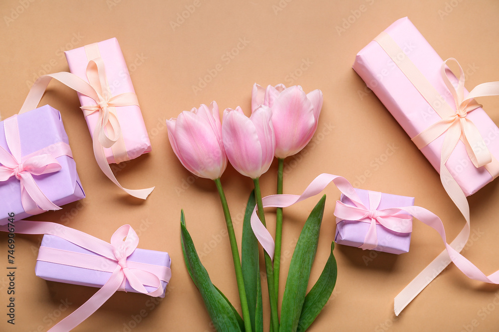 Gift boxes and pink tulips on beige background. Top view Gift boxes and pink tulips on beige background. Top view