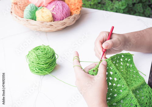 Close-up of woman hand knitting with green wool