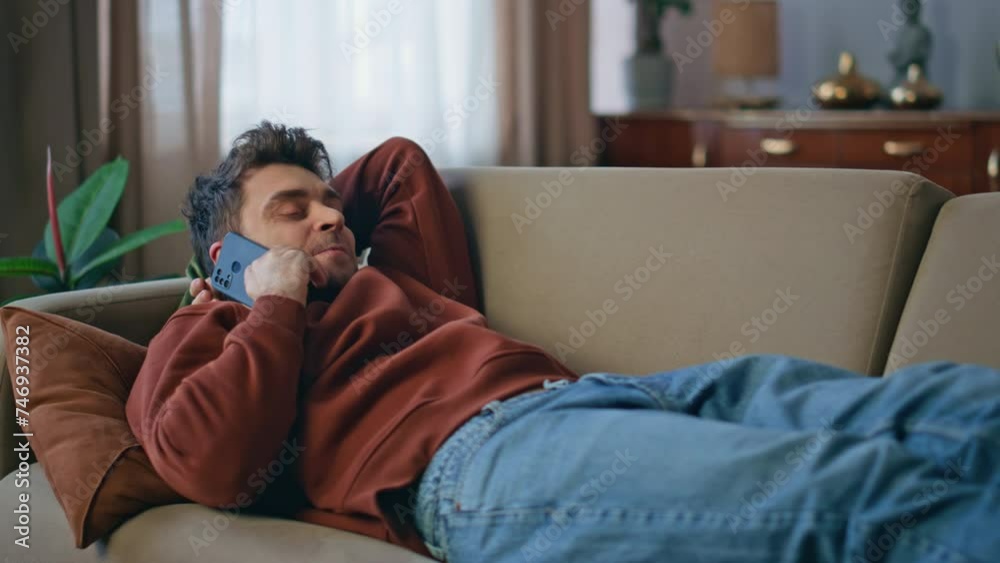Chilling guy calling smartphone lying on home sofa close up. Smiling man talking Chilling guy calling smartphone lying on home sofa close up. Smiling man talking