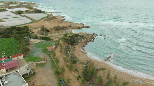 Aerial view of Kapparis in Paralimni, Cyprus, reveals a serene coastal area where agricultural fields meet the sandy beach and rocky shoreline, with the Mediterranean Sea stretching into the horizon. photo